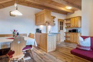 a kitchen with wooden cabinets and a table and chairs at Kranebitterhof Apt Alpenrose in Valdaora