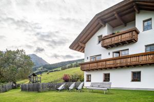 a building with a deck and chairs in the yard at Kranebitterhof Apt Alpenrose in Valdaora