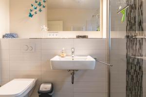 a bathroom with a sink and a toilet at Ferienwohnung Büsumperle weiß in Büsum