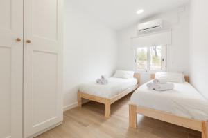 a white room with two beds and a window at Casita Palmeras in Canyelles
