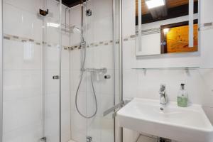 a white bathroom with a shower and a sink at Ferienhaus Bussardnest in Tennenbronn +25 photos