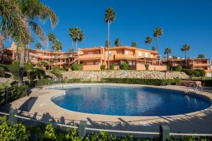 a swimming pool in front of a building with palm trees at Fantastic beachfront apartment in Estepona