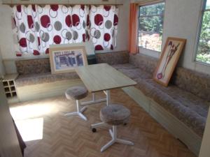 a room with a bench with a table and two stools at Mobil'Home du Sancillon in Charentay +2 photos