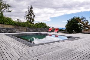 a swimming pool with two chairs and a wooden deck at Ponta da Amora in Ponta Garça