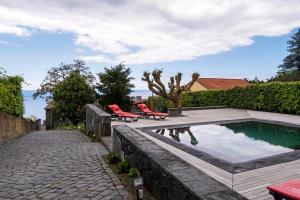 a backyard with a pool and two red chairs at Ponta da Amora in Ponta Garça