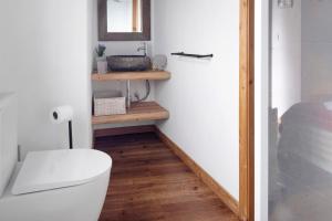 a bathroom with a white toilet and a wooden shelf at Ponta da Amora in Ponta Garça +31 photos
