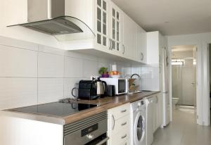 a white kitchen with a sink and a microwave at Fabulous upper floor sea view in San Agustin