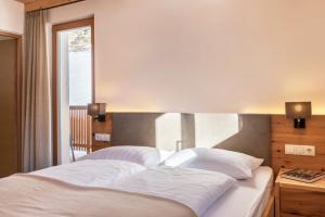 a bedroom with a bed with white sheets and a window at Villa Solinda App Rossini in Selva di Val Gardena