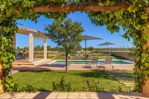 a view through an archway into a garden with a pool at Sa Vinya Jove in Biniali