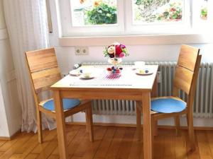 a table with two chairs and a vase of flowers on it at Apartment Am Birnbaum in Reutlingen