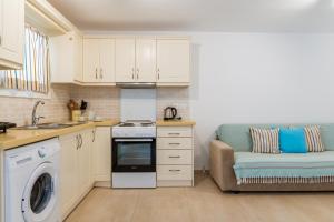 a kitchen with white cabinets and a couch in it at Afroditi Ftelia Yasemi b in Mykonos +15 photos