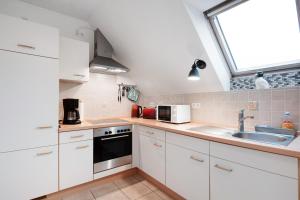 a kitchen with white cabinets and a sink and a window at Ferienwohnung Abendsonne in Lehe