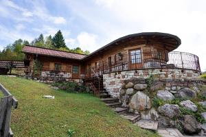 a log cabin with a stone wall and a building at Baita Chalet Alabama in Arsiè