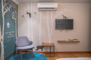 a room with a tv and a chair and a tree mural at Sojourn Spa Hotel Kuala Lumpur in Kuala Lumpur