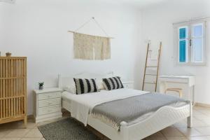 a white bedroom with a white bed and a ladder at Olympos Blue in Karpathos