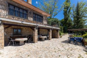 a stone patio with tables and chairs in front of a building at Casa Rural Las Yernas in La Serrada