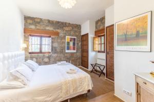 a bedroom with a white bed and a stone wall at Casa Rural Las Yernas in La Serrada +30 photos