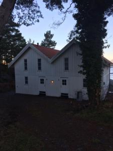a white barn with a red roof in a yard at Sponavik Camping in Stord