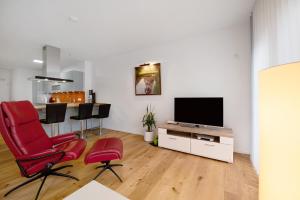 a living room with red chairs and a flat screen tv at Ferienwohnung an der Gustavsburg in Homburg