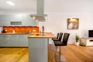 a kitchen with white cabinets and a island with black chairs at Ferienwohnung an der Gustavsburg in Homburg