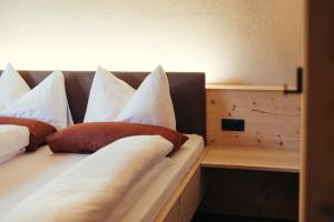 a bed with white and red pillows on it at Obertimpflerhof Wohnung Lola in Verano