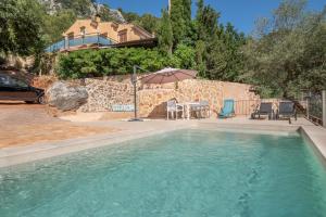 a swimming pool with a table and an umbrella at Casa Caimari in Caimari