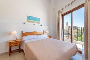 a bedroom with a bed and a large window at Es Campanar in Santanyi +18 photos