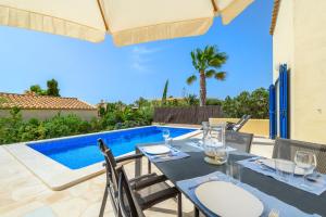 a dining table with chairs next to a swimming pool at Casa Folara in Cala Llombards