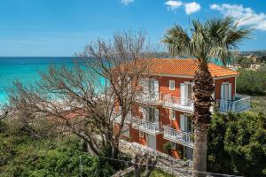 a building with a palm tree in front of the ocean at Angela partial sea view 5 in Kefallonia