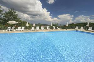 a large blue swimming pool with chairs and umbrellas at Mono Le Lecce 38b in Capoliveri