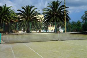 a tennis net on a tennis court with palm trees at Mono Le Lecce 38b in Capoliveri