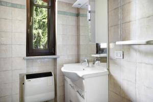 a white bathroom with a sink and a window at Anemone Tano di Grich in Cesani