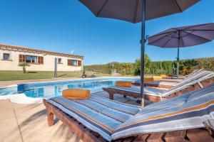 a swimming pool with lounge chairs and an umbrella at Can Siurell in Artá