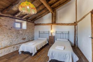 a bedroom with two beds and a chandelier at La Botica De Maderuelo in Maderuelo