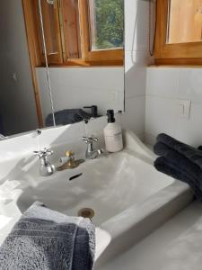 a white bathroom sink with a mirror and towels at studio Le Cabanon in Doussard