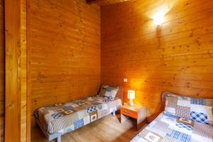 two beds in a room with wooden walls at Villaggio Anemone Chalet Scoiattolo in Capanne di Sillano