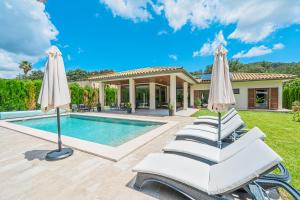 a villa with a swimming pool and two white umbrellas at Villa Sa Olivera in Crestatx