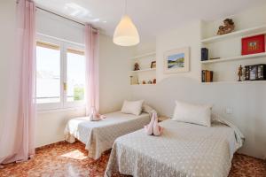 two beds in a room with white walls and windows at Casa Beramendi in Torremolinos +22 photos