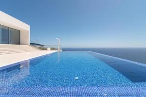 a swimming pool with blue water in front of a house at Villa Camacho - Ultra Luxury in Calheta