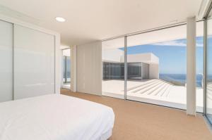a bedroom with a white bed and a view of the ocean at Villa Camacho - Ultra Luxury in Calheta