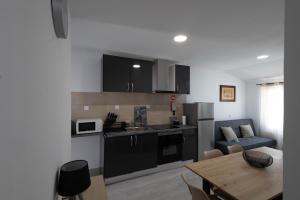 a kitchen with black cabinets and a table and a dining room at Casa dos Avós in Santa Eulália