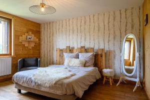 a bedroom with a large bed and a mirror at Chalet le Brusyna avec jacuzzi in Saint-Maurice-sur-Moselle