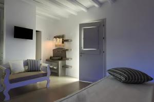 a room with a bed and a chair and a door at Echinousa Kimolos Maisonette no1 in Kimolos