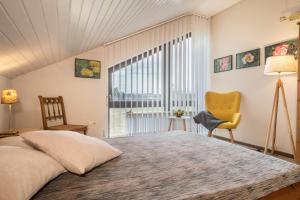 a bedroom with a bed and a chair and a window at Schwippl in Meckenbeuren
