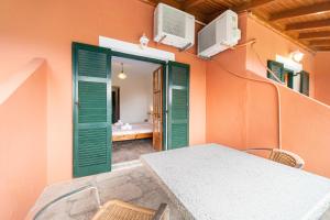 a room with a table and green shutters and a bedroom at Arianna Studio Ground Floor 7 in Paleokastritsa