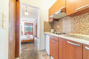 a kitchen with wooden cabinets and a room with a bed at Arianna Studio Ground Floor 7 in Paleokastritsa