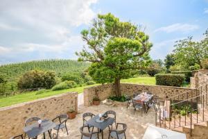 a patio with tables and chairs and a tree at Brotes Appartamento Mandorlo in Sovicille