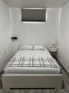 a white bedroom with a bed and a window at Departamento privado in Tijuana