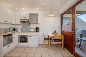 a kitchen with white cabinets and a table with chairs at Gästehaus Heinemann - Og4 in Langenargen +16 photos