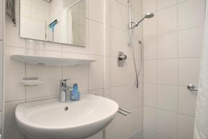 a white bathroom with a sink and a shower at Gästehaus Heinemann - Og4 in Langenargen